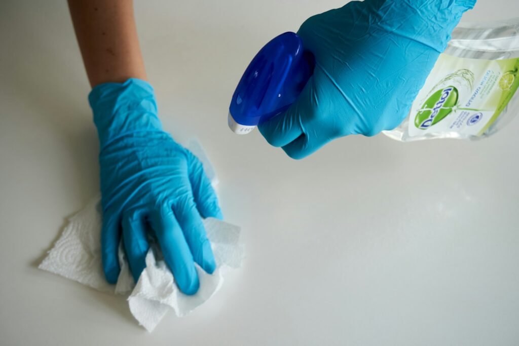 Gloved hands wiping down a white surface